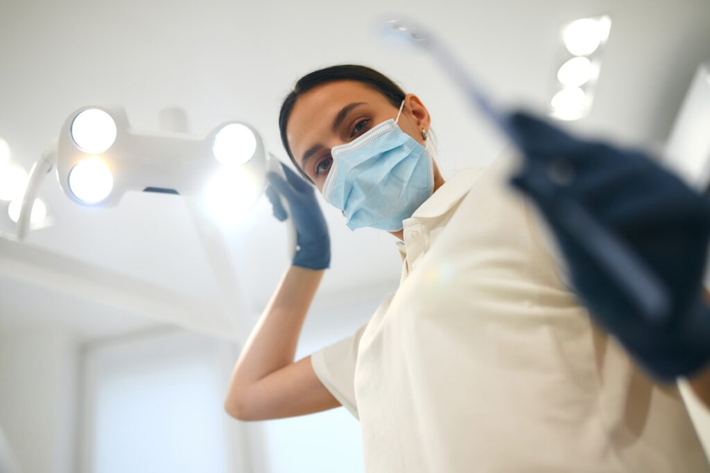 A woman leans over a patient to perform teeth whitening in Craven County