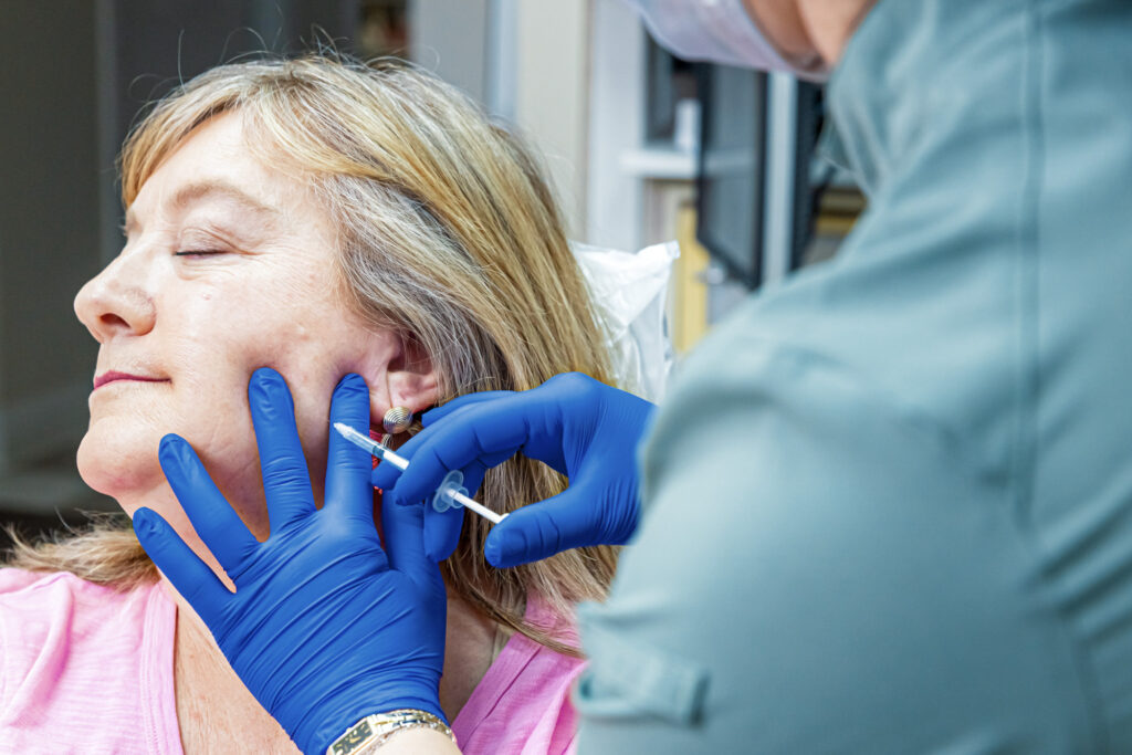 A woman turns her head as a provider injects Botox for TMJ in Craven County.
