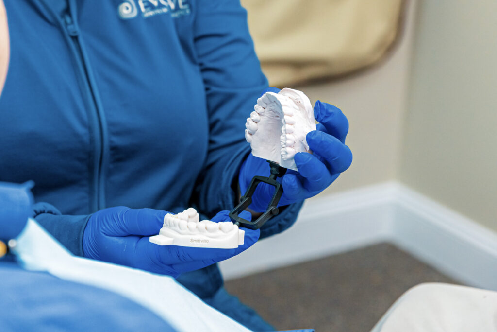A member of our team holds a set of plaster teeth molds and explains the process for installing dental bridges in Craven County.
