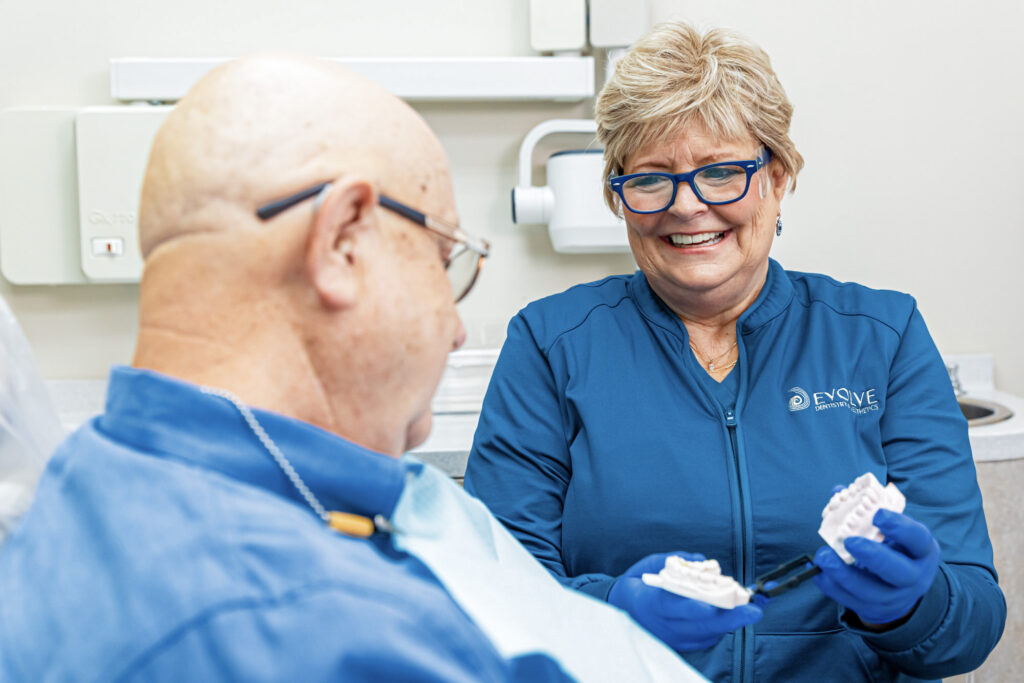 A provider laughs with a patient as she shows two options for dental implants in Craven County.